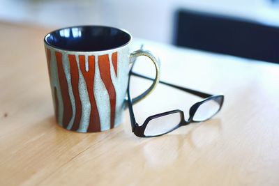 Close-up of eyeglasses and mug on table