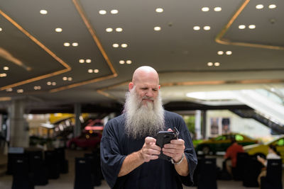 Full length portrait of man holding camera while standing on ceiling