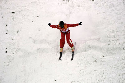 Full length portrait of happy woman standing on snow