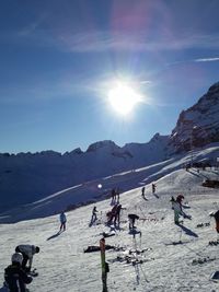 People walking on snow covered mountain against clear sky