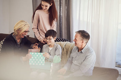 Smiling boy receiving birthday gifts from family at home