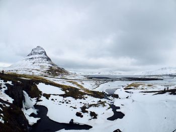 Scenic view of snow covered mountains against cloudy sky