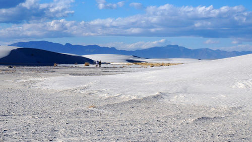 Two distant people walking on snow covered field