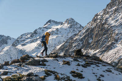 Low angle view of person climbing mountain during winter