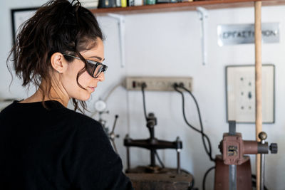 Profile portrait of female jewler working in well lit home studio