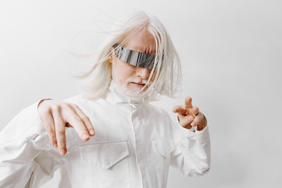 Portrait of young woman wearing mask against white background