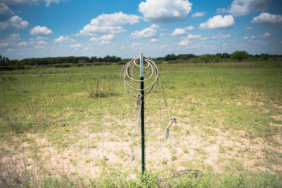 Metal fence on field against sky