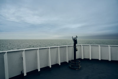 Rear view of man standing on railing against sea