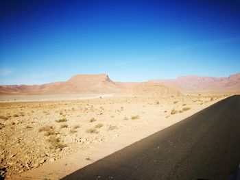 Scenic view of desert against clear blue sky