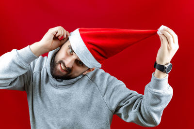 Midsection of man with arms raised against red background