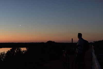 Rear view of silhouette man looking at sunset