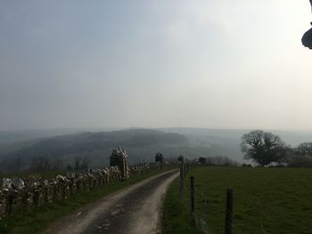 Road amidst field against sky