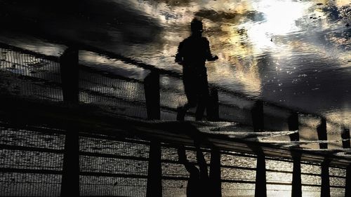 Silhouette man standing by railing