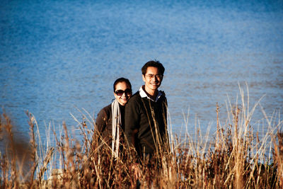 Portrait of couple standing on field against sea