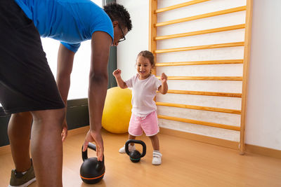 Little kid lifting kettlebell near father