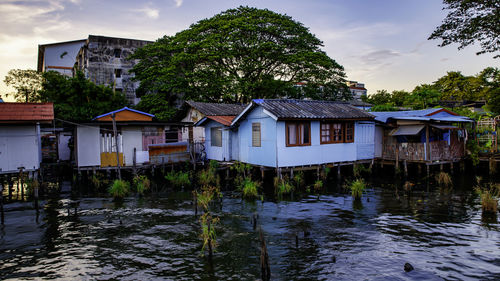 Houses by river and buildings against sky