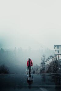 Rear view of man walking on road against sky