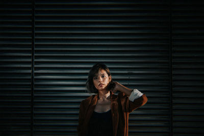 Portrait of beautiful young woman standing against wall