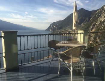 Chairs and tables by lake against sky