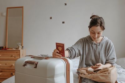 Woman with the baggage and passport at home, preparing to flight