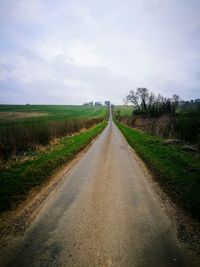 Road amidst field against sky