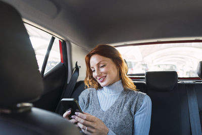 Happy woman using smart phone in car