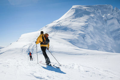 Rear view of people on snowcapped mountain against sky