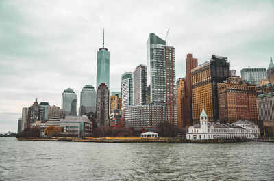 Modern buildings by river against sky in city