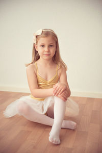 Portrait of ballet dancer sitting on wooden floor