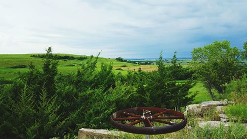 Scenic view of wheel on grass against cloudy sky