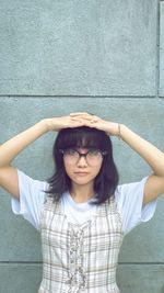 Portrait of beautiful young woman standing against wall