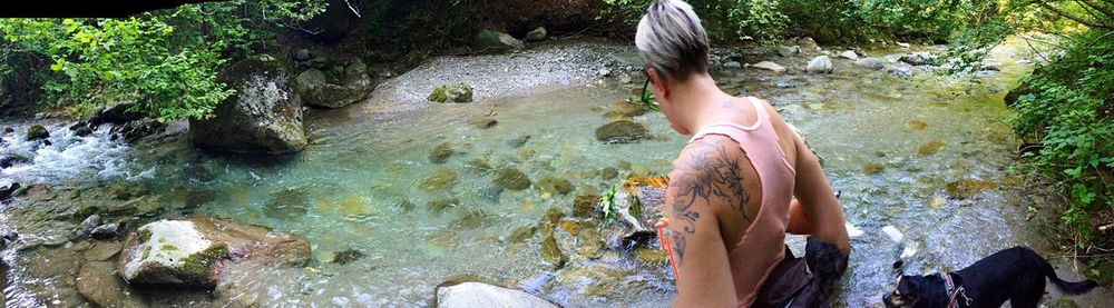 Rear view of woman with dog by stream