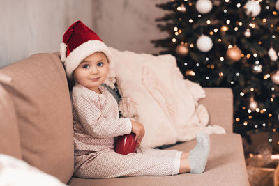 Portrait of cute girl sitting on sofa at home