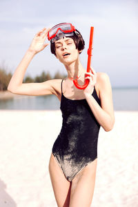 Young woman with arms raised standing at beach