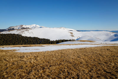 Scenic view of snowcapped mountains against clear blue sky