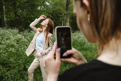 Rear view of woman photographing with mobile phone