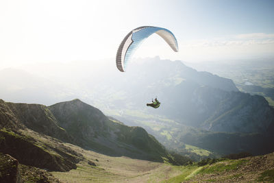 View of man paragliding over landscape against sky