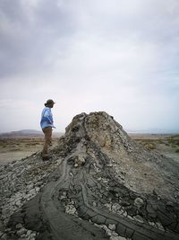 Man standing on rock against sky