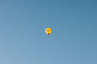 Low angle view of hot air balloons against clear blue sky