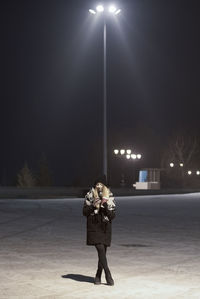 Woman standing on street light at night