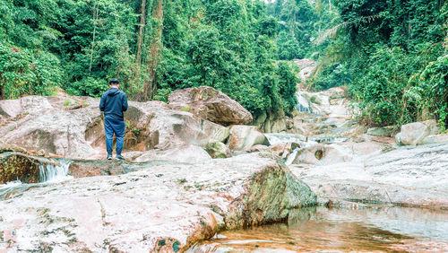 Man standing by rocks in river