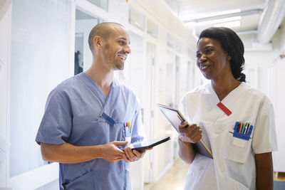 Happy medical professionals in uniform discussing at hospital corridor