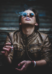 Portrait of young woman smoking on sunglasses