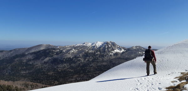 Rear view of person on snowcapped mountain against sky