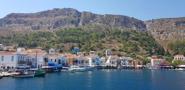 Sailboats in city by buildings against clear sky