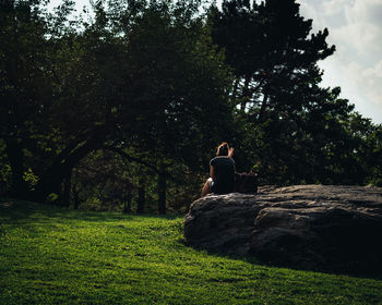 Man sitting on field against trees