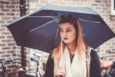 Close-up of beautiful woman holding umbrella on street in rain