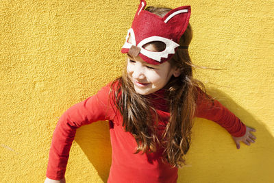 Portrait of little girl with animal mask in front of yellow wall