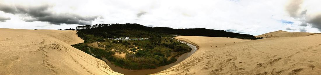 Panoramic view of sand dunes against sky