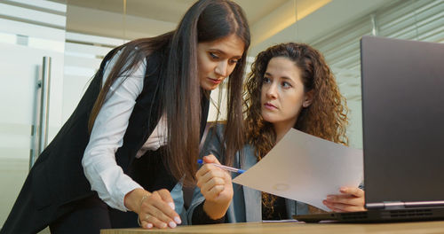 Diverse coworkers having corporate meeting and standing in front of laptop discussing matters. 